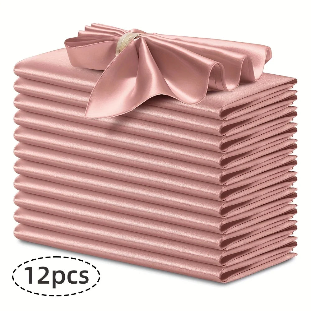 A stack of twelve silky satin pink dinner napkins with a decorative bow on top.