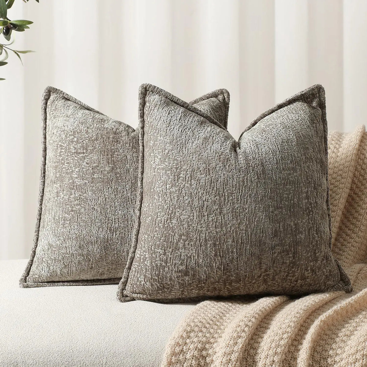 A close-up of a textured gray chenille throw pillow resting on a light-colored sofa or blanket.
