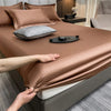 A close-up of a luxurious brown fitted bed sheet with pillows and a dark tray on the bed.
