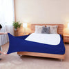 A dark blue high-stretch elastic box spring cover is displayed on a wooden bed frame with fluffy pillows.