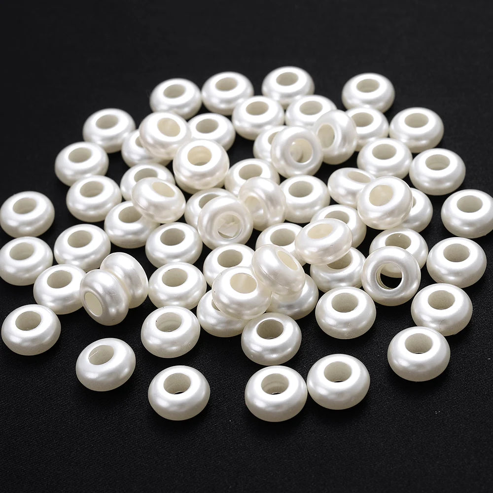 A pile of small, round, white imitation pearl flower spacer beads for DIY jewelry.