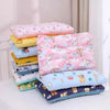 A stack of reversible cartoon animal fiber pillows in pink, yellow, blue, and purple for infants.