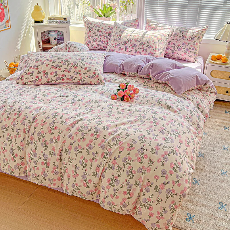 A floral printed bedding set featuring pink and purple patterns on a bed with matching pillows.