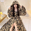 A woman wearing a long leopard print flannel kimono robe indoors.