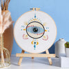 A beginner embroidery starter kit featuring star patterns displayed on a circular canvas with a wooden easel.