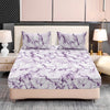 A bed dressed with a white and purple marble print fitted sheet set and matching pillowcases.