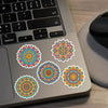 Colorful mandala graffiti stickers are displayed on a laptop keyboard and surface.