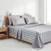 A gray striped satin bedding set displayed on a wooden bed with white decor.