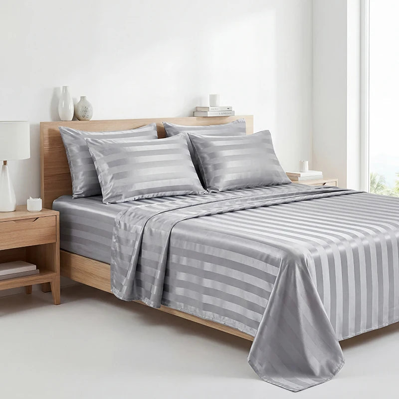 A gray striped satin bedding set displayed on a wooden bed with white decor.