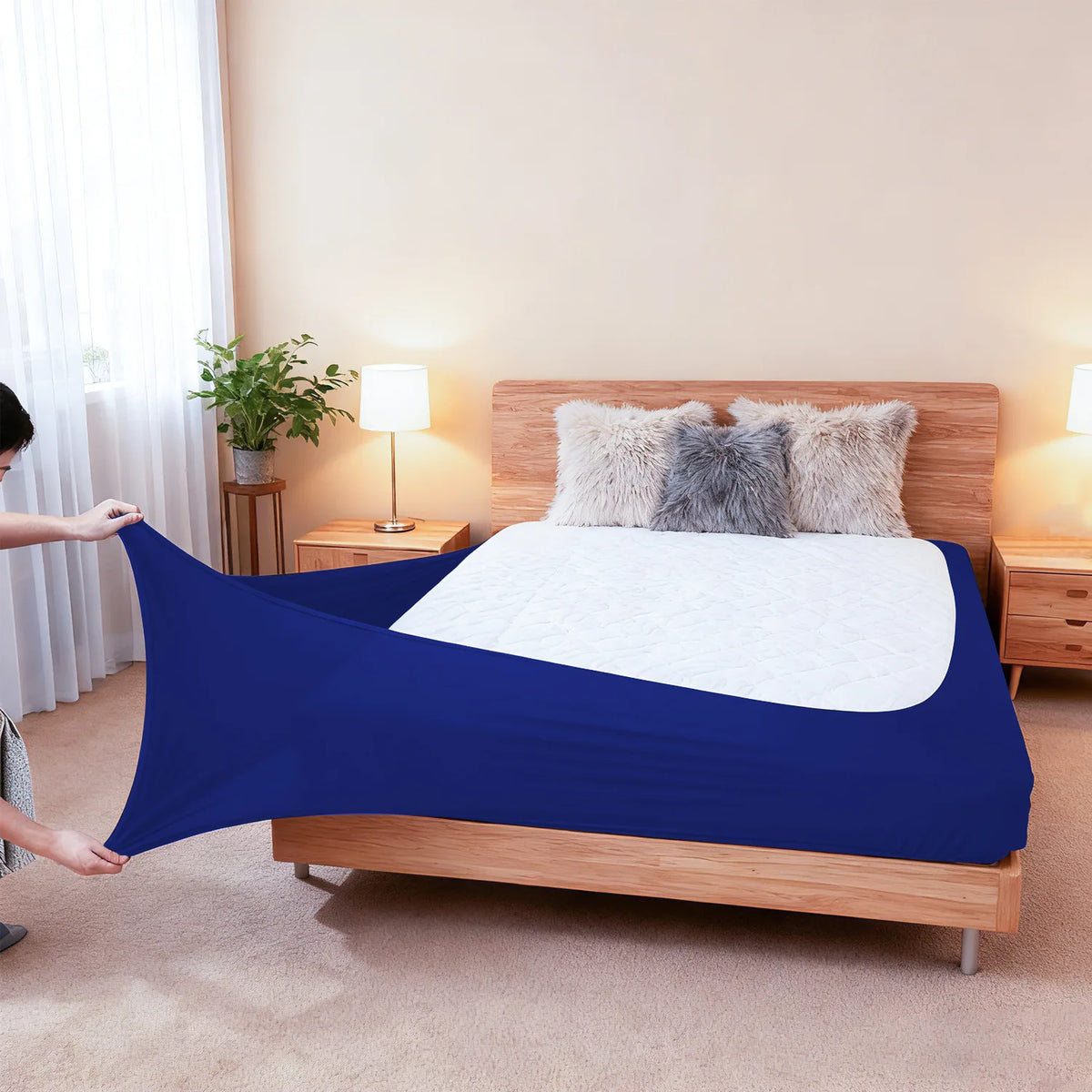 A dark blue high-stretch elastic box spring cover is displayed on a wooden bed frame with fluffy pillows.