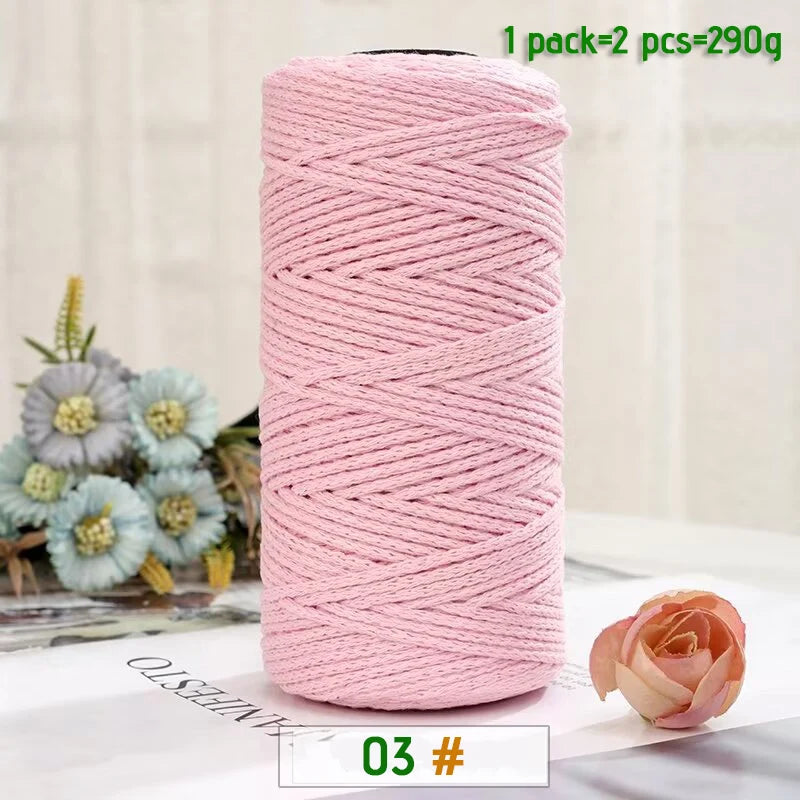 A pink ball of medium-thick hand-woven cotton yarn for crafting, with a single rose visible nearby.
