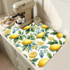A yellow lemon printed non-slip dish drying mat placed on a kitchen counter next to a milk frother.