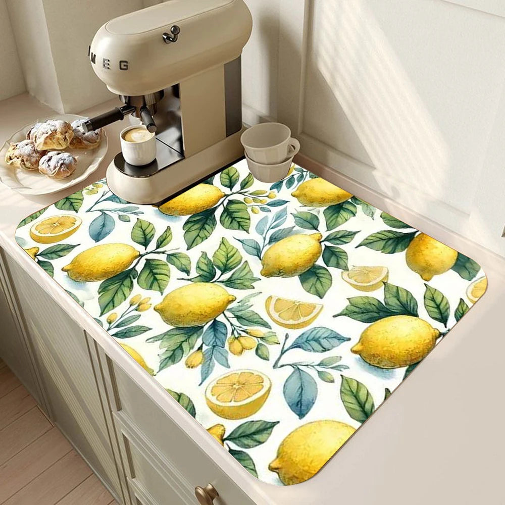 A yellow lemon printed non-slip dish drying mat placed on a kitchen counter next to a milk frother.