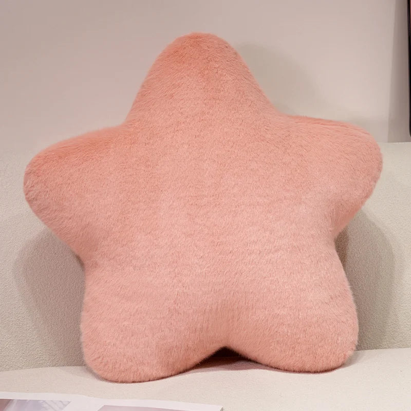 A soft, pink star-shaped decorative throw pillow with a fluffy texture.
