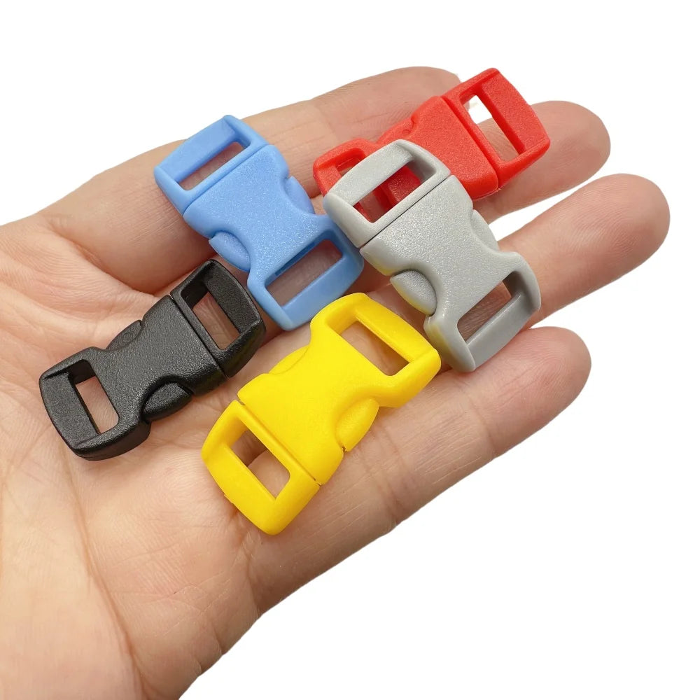 A hand holds several colorful adjustable plastic paracord buckle bracelets in various shades of red, blue, gray, and yellow.