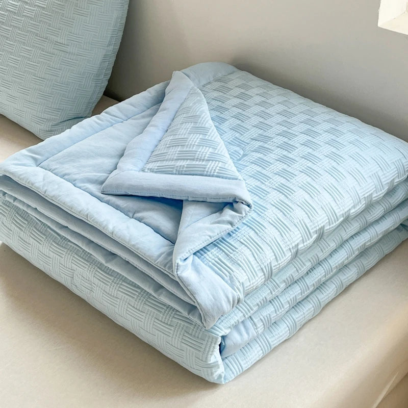 Light blue breathable waffle quilt folded neatly on a white surface.