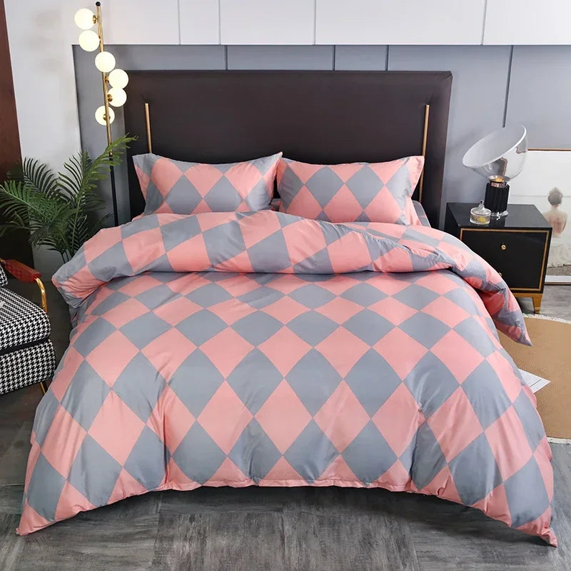 A pink and gray diamond patterned duvet cover set displayed on a bed with dark gray bedding and modern decor.