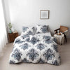 A white duvet cover set with a blue and gray floral geometric pattern displayed on a bed against a white wall.