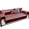 A richly embroidered red sofa cover featuring deep maroon velvet accents and patterned pillows.