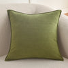 A square olive green chenille throw pillow resting on a light beige textured sofa.