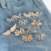 Gold and silver butterfly and crescent moon button clips arranged on a denim fabric