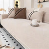 A light beige chenille sofa protector cover with black striped accent pillows and a white mug on the surface.