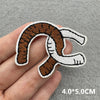 An embroidered iron-on patch depicting a coiled brown and white snake design being held by a hand.