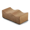 A tan ergonomic memory foam leg support pillow shown from the side.
