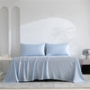 Light blue luxury organic bamboo bed sheet set draped over a bed.