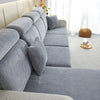 A light gray stretchable chenille sofa cushion cover on a sectional sofa with white trim and natural light.