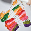 A collection of vibrant 250-color polyester cross-stitch threads in various shades of orange, green, pink, and purple arrange