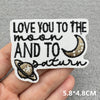 Black embroidered patch with the text Love you to the moon and to Saturn on a white background