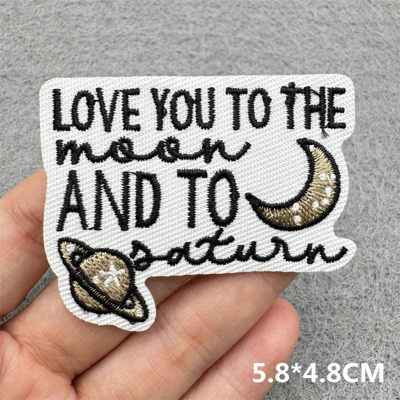 Black embroidered patch with the text Love you to the moon and to Saturn on a white background