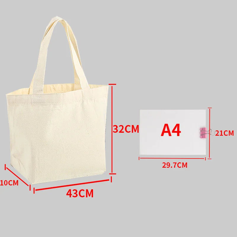 A beige canvas tote bag with handles shown next to an A4 sized card for scale.