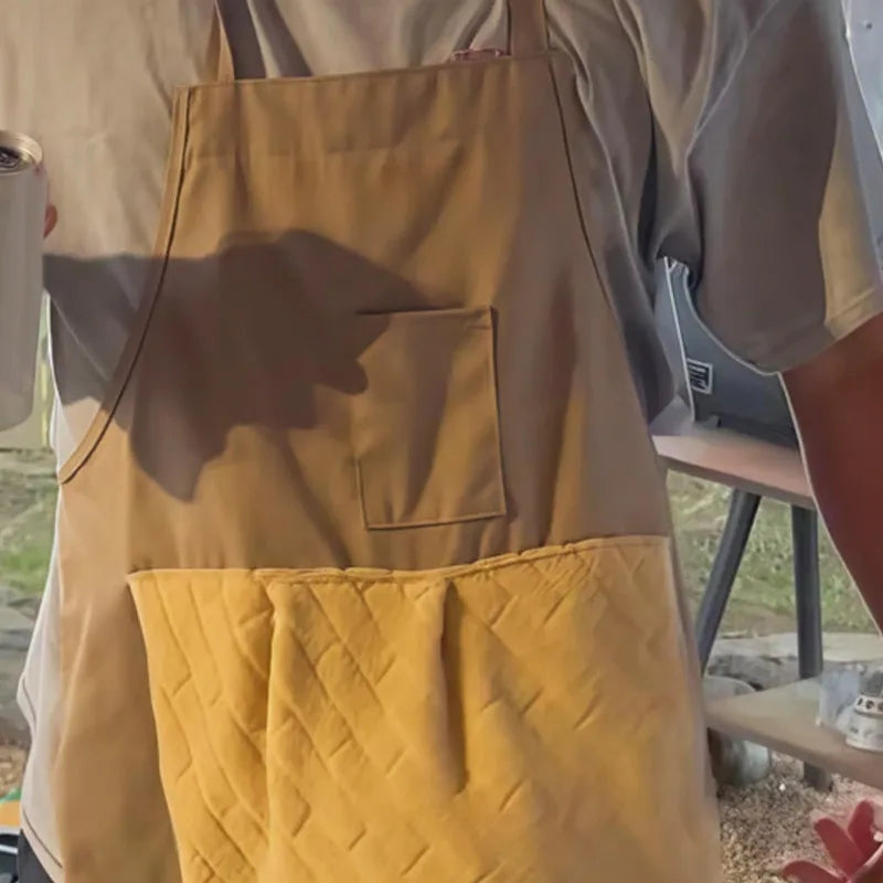 A light tan apron with a yellow quilted pocket on the front, shown in a close-up.