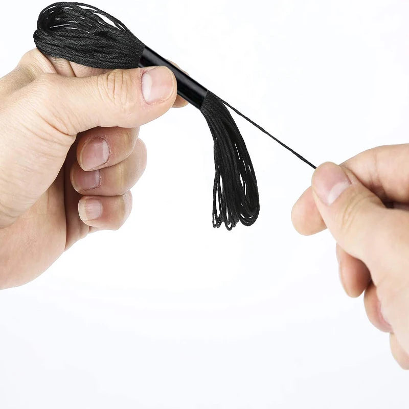 A hand holds a black embroidery floss set with a thin tail, showing the texture of the thread.