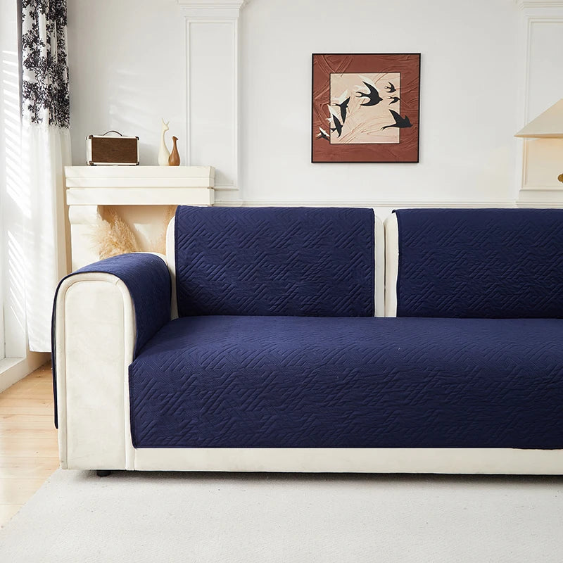 A navy blue geometric quilted sofa cushion cover on a white frame in a bright room.