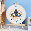 A beginner embroidery starter kit featuring a large eye design with star patterns on a white canvas.