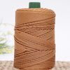 A spool of brown crochet ice rope with a green cap resting on a woven mat.