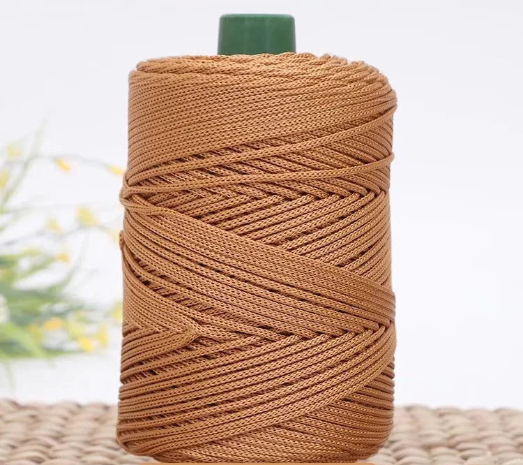 A spool of brown crochet ice rope with a green cap resting on a woven mat.
