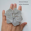 A hand holds a white rhinestone flower applique patch, measuring 8.5cm or 3.35 inches.
