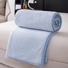 Light blue flannel throw blanket folded neatly on a white sofa