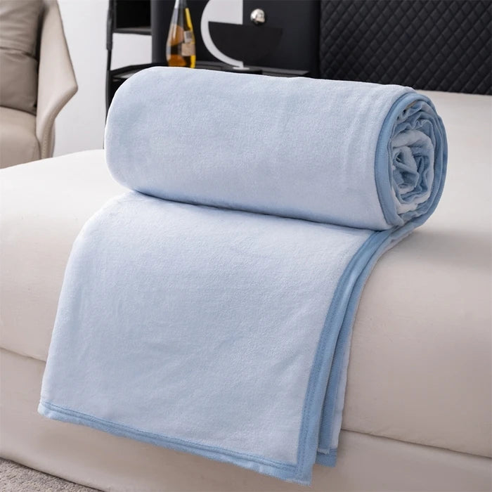 Light blue flannel throw blanket folded neatly on a white sofa
