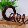 Roll of dark brown satin ribbon with a white core resting on a wooden surface.