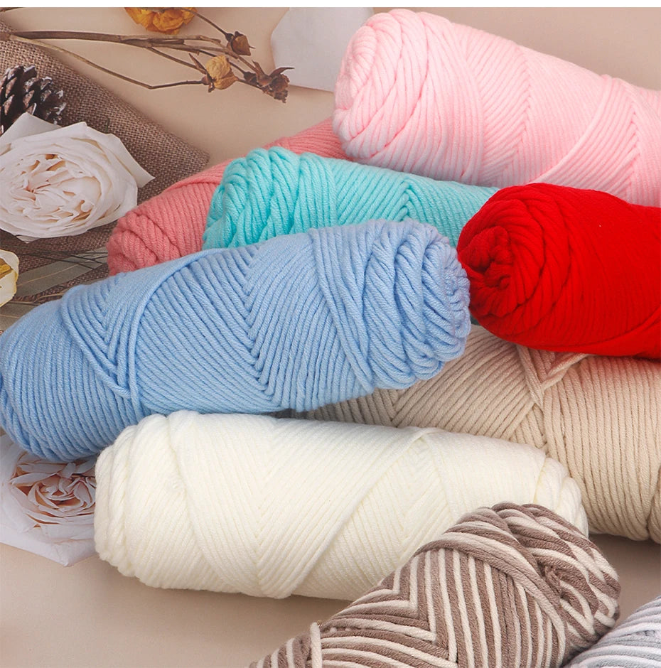 A collection of pink, blue, red, and cream colored yarn skeins rolled up on a surface.