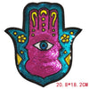 A pink and blue sequin iron-on patch featuring a handprint design with an eye in the center.