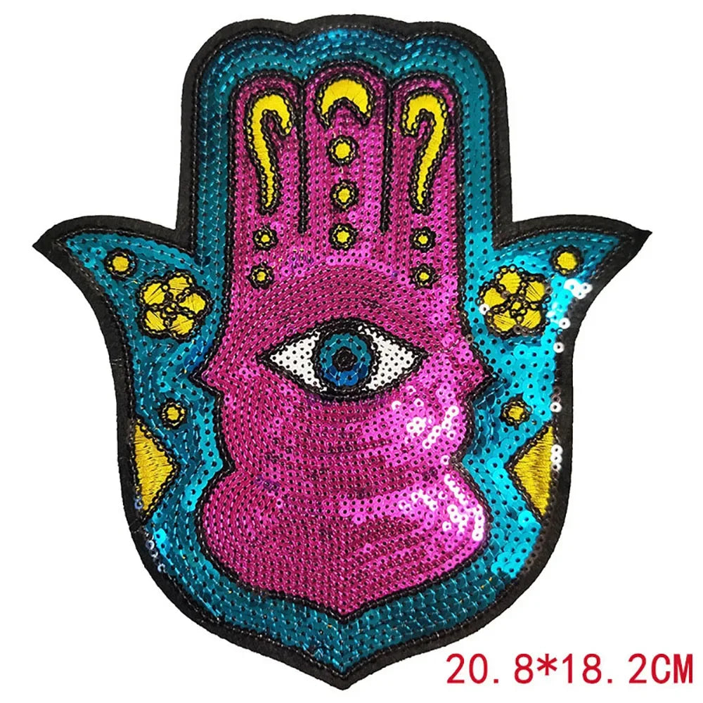 A pink and blue sequin iron-on patch featuring a handprint design with an eye in the center.