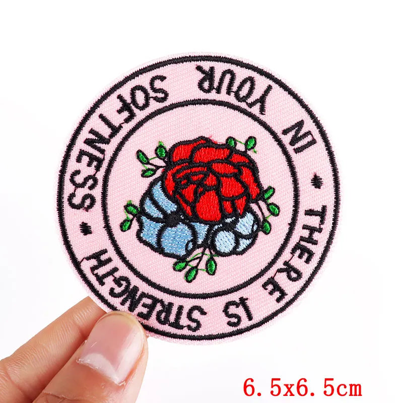 Pink embroidered iron-on patch with text and a red rose design on a pink background