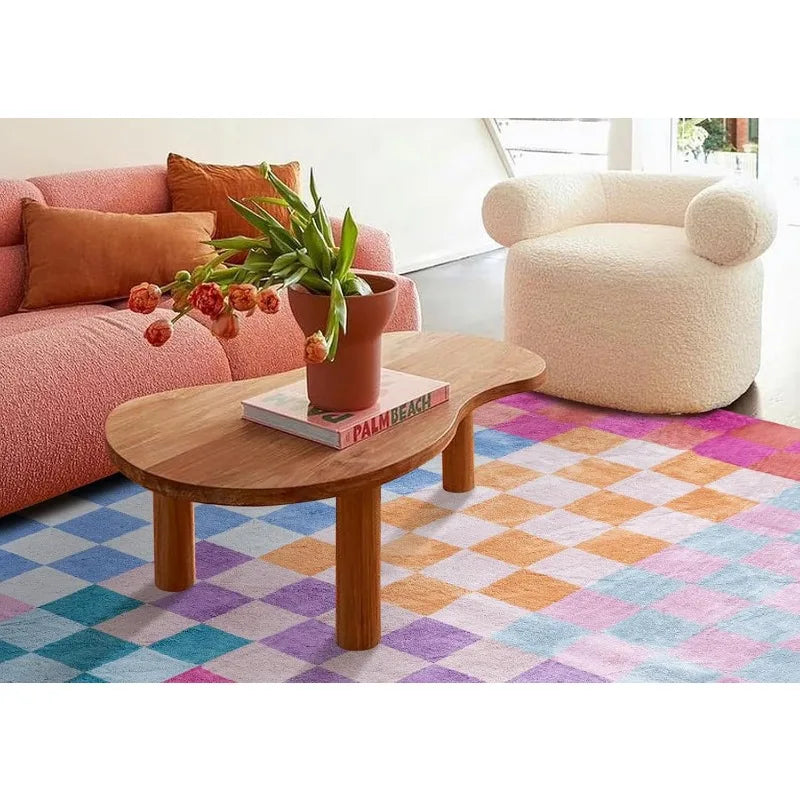 A light pink and orange retro checkerboard geometric rug placed in front of a wooden coffee table.