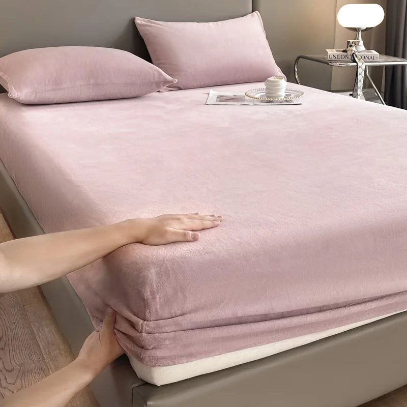A close-up of a pink luxury velvet bedding set featuring a sheet and pillow, resting on a bed.